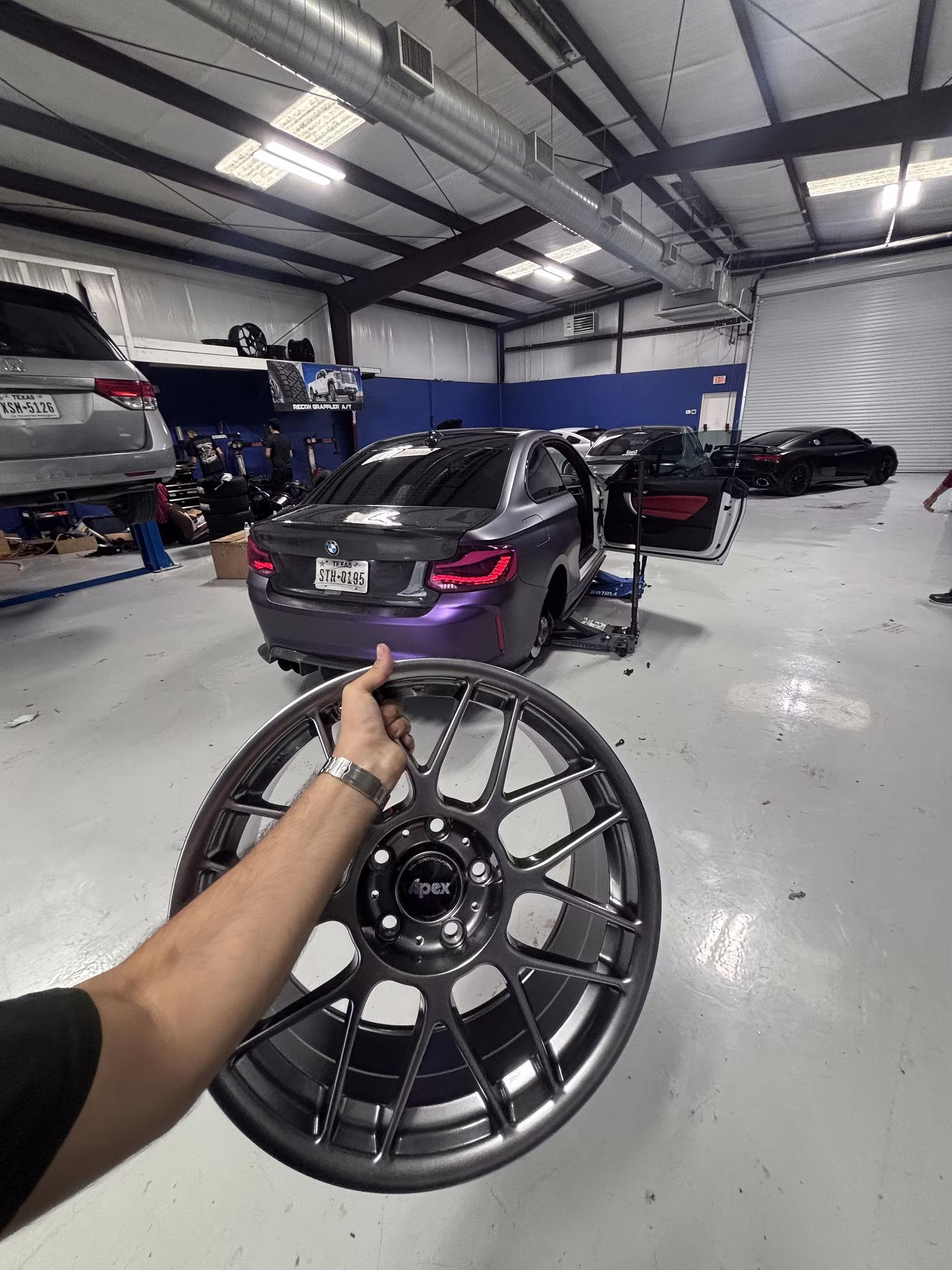 Habibi technician holding a performance wheel beside a customer vehicle